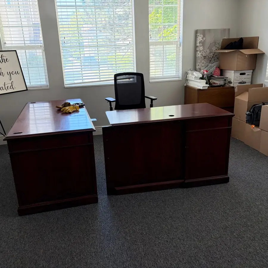 Office cleanout in progress with desks, office chair and stacked moving boxes ready for removal