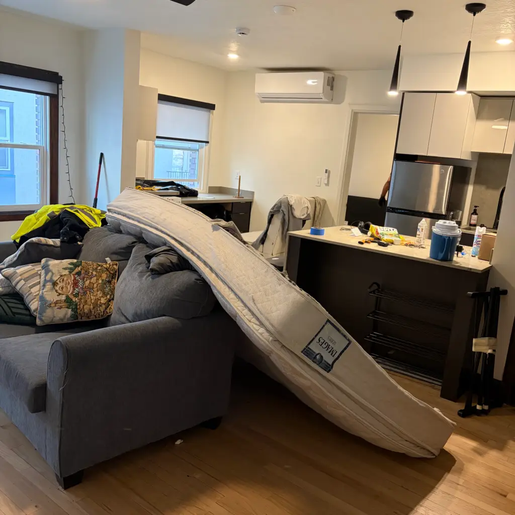 Apartment living room with a couch and mattress staged for removal
