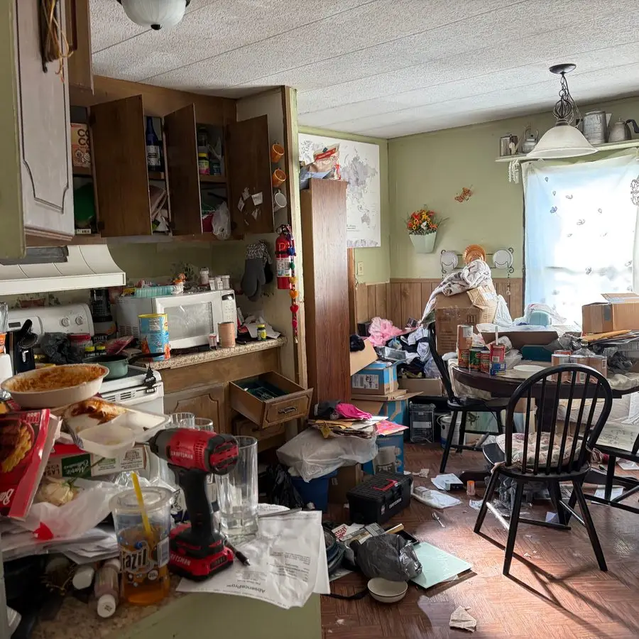 Cluttered kitchen and dining room packed with boxes, bags and household clutter before a Junk Hogs home cleanout